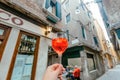 Traditional Italian cocktail Aperol spritz in hand of bar customer. Old street tour with glass of tasty refreshing drink