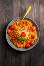 Traditional Italian cuisine. Plate with spaghetti, tomato sauce, cherry tomatoes, mushrooms and basil on a dark wooden Royalty Free Stock Photo