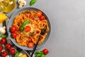 Traditional Italian cuisine. Plate with spaghetti, tomato sauce, cherry tomatoes, mushrooms and basil on a gray Royalty Free Stock Photo