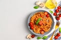Traditional Italian cuisine. Plate with spaghetti, tomato sauce, cherry tomatoes, mushrooms and basil on a light gray Royalty Free Stock Photo