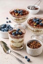 Traditional Italian dessert tiramisu with blueberries in glass. Individual trifle. Homemade layered cake with berries in cup.