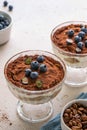 Traditional Italian dessert tiramisu with blueberries in glass. Individual trifle. Homemade layered cake with berries in cup.