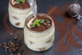 Traditional Italian dessert tiramisu decorated with cocoa powder and green mint in glass jar Royalty Free Stock Photo