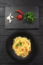 A traditional Italian dish. Pasta on a dark plate. Next to the ingredients parsley chili pepper, garlic Royalty Free Stock Photo