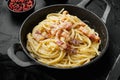 Traditional italian dish spaghetti carbonara with bacon in a cream sauce, in cast iron frying pan, on black stone background Royalty Free Stock Photo