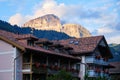 Traditional Italian house in Campitello di Fassa, with Dolomites mountain peaks lit by orange sunset light in the background Royalty Free Stock Photo