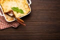 Traditional Italian lasagna in casserole pan on wooden table