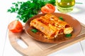 Traditional Italian pasta cannelloni. Baked tubes stuffed with minced meat with parmesan cheese and bechamel sauce on a white wood Royalty Free Stock Photo