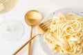 Traditional Italian pasta - Fetuccini Alfredo on a white table with golden appliances