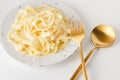 Traditional Italian pasta - Fetuccini Alfredo on a white table with golden appliances