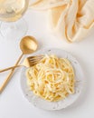 Traditional Italian pasta - Fetuccini Alfredo on a white table with golden appliances