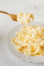 Traditional Italian pasta - Fetuccini Alfredo on a white table with golden appliances