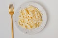 Traditional Italian pasta - Fetuccini Alfredo on a white table with golden appliances