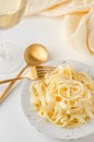 Traditional Italian pasta - Fetuccini Alfredo on a white table with golden appliances