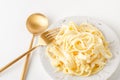 Traditional Italian pasta - Fetuccini Alfredo on a white table with golden appliances