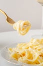 Traditional Italian pasta - Fetuccini Alfredo on a white table with golden appliances