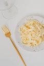 Traditional Italian pasta - Fetuccini Alfredo on a white table with golden appliances