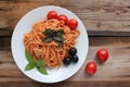 Traditional Italian pasta and ingredients on the white plate on rustic wooden table background. Long spaghetti with tomato sauce, Royalty Free Stock Photo