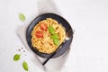 Traditional Italian pasta spaghetti with tomatoes, tomato sauce, basil on a dark plate on a light gray background. Royalty Free Stock Photo