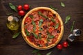 Traditional italian pizza with ham, cheese, tomatoes and olives on rustic wooden background. Royalty Free Stock Photo