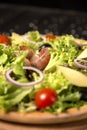 Close up of Traditional Italian pizza with jamon Serrano in focus, Parmesan cheese, black olives and cherry tomatoes Royalty Free Stock Photo