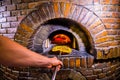 Traditional Italian pizzeria background with stone stove oven, pizza and pizza maker hands.