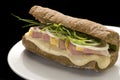 Traditional Italian sandwich with ham, cheese and onion on a white plate