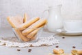 Traditional italian savoiardi or ladyfingers biscuits in a glass bowl and pieces of cookies and sugar on the table, a white cup of