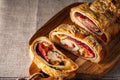 Traditional Italian Stromboli stuffed with cheese, salami, red pepper and spinach. Photo in a dark style. Royalty Free Stock Photo