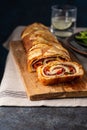 Traditional Italian Stromboli stuffed with cheese, salami, red pepper and spinach. Photo in a dark style. Royalty Free Stock Photo