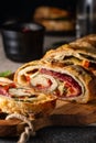 Traditional Italian Stromboli stuffed with cheese, salami, red pepper and spinach. Photo in a dark style. Royalty Free Stock Photo