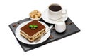 Traditional Italian Tiramisu dessert square portion on ceramic plate and cup of fresh espresso coffee on stone serving