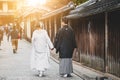 Traditional Japanese ceremony wedding lovely day, silhouettes of married couple holding red paper umbrella in hands, kissing under