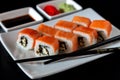 Traditional Japanese cuisine. Philadelphia sushi roll made of fresh salmon, avocado and cream cheese with black rice Royalty Free Stock Photo