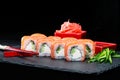 Traditional Japanese cuisine. Selective focus on Philadelphia sushi rolls with salmon, cream cheese, rice and cucumber on dark ba Royalty Free Stock Photo