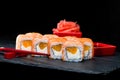 Traditional Japanese cuisine. Selective focus on sweet sushi rolls with salmon, cream cheese, rice and orange on dark background Royalty Free Stock Photo