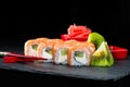 Traditional Japanese cuisine. Selective focus on sweet sushi rolls with salmon, cream cheese, rice and kiwi on dark background, n Royalty Free Stock Photo