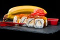 Traditional Japanese cuisine. Sweet sushi rolls with salmon, cream cheese, rice and banana was poured with jam on dark background Royalty Free Stock Photo