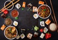 Traditional Japanese food - sushi, rolls, rice with shrimp and udon noodles with chicken and mushrooms on a dark background. Royalty Free Stock Photo