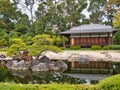 A traditional Japanese house and small lake, with manicured garden and small trees Royalty Free Stock Photo