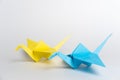 Traditional Japanese origami cranes made of blue and yellow paper on a white background. Pair of colorful paper birds