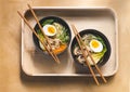 Traditional japanese Ramen soup with mushrooms, Bok Choy, greens in two black bowls on a wooden tray