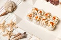 Japanese Volcano Sushi Roll pieces with raw scallop and Tobiko caviar on carton delivery takeaway box. white wooden background Royalty Free Stock Photo