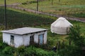 Traditional Kyrgyz yurt, next to small white brick house.