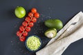 Traditional latinamerican mexican sauce guacamole in ceramic bowl and ingredients on dark background. Royalty Free Stock Photo