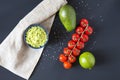 Traditional latinamerican mexican sauce guacamole in ceramic bowl and ingredients on dark background. Royalty Free Stock Photo