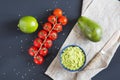 Traditional latinamerican mexican sauce guacamole in ceramic bowl and ingredients on dark background. Royalty Free Stock Photo