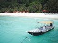 A traditional longtail boat floats in clear water on the island paradise of Pulau Redang, Malaysia.