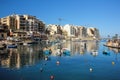 Traditional maltese boats reflected in blue water of harbour San Giljan Royalty Free Stock Photo