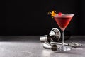 Traditional Manhattan cocktail with cherry on gray stone and black background.